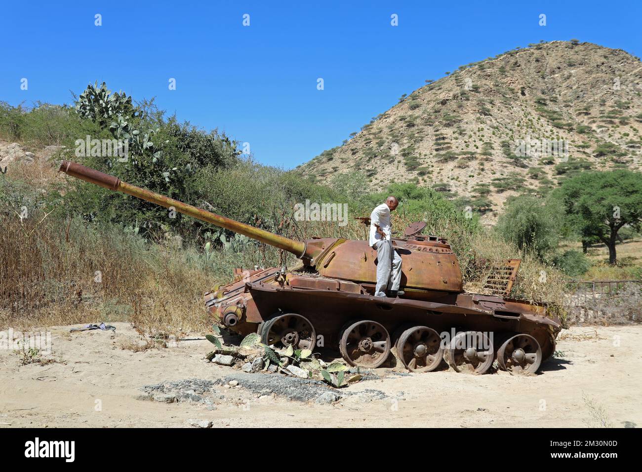 Tourist standing on an old army tank in Eritrea which was left in the countryside after the civil war Stock Photo
