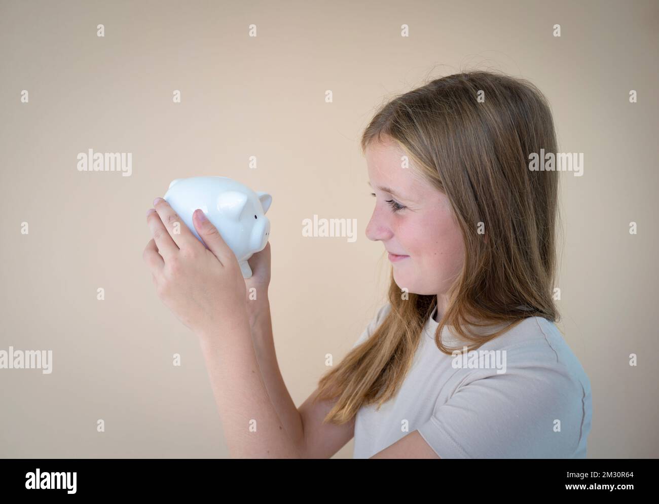cool young girl in front of brown background holding piggy bank in her ...