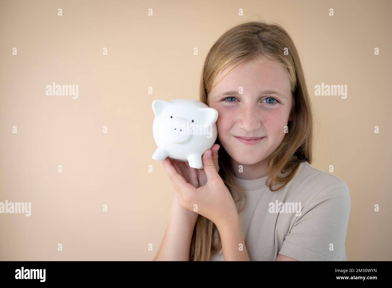 cool young girl in front of brown background holding piggy bank in her ...