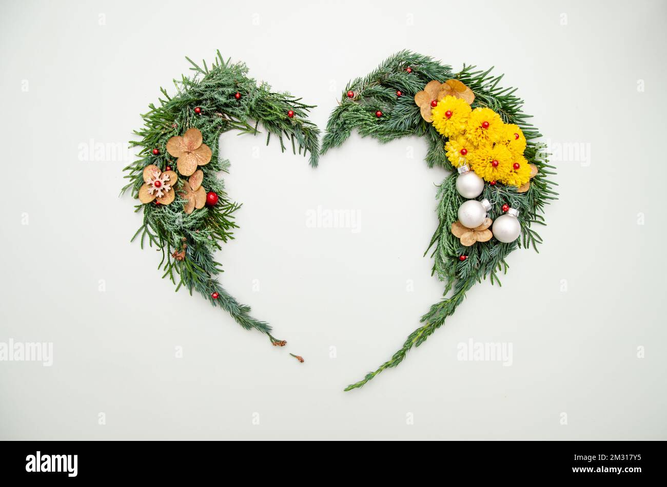 Christmas composition. Heart symbol made of pine, cypress, thuja branches branches, balls, berries and wood decorations. Christmas, winter, new year c Stock Photo