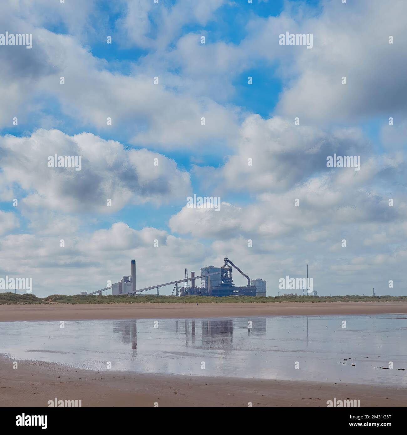 A massive industrial landscape, with the now-demolished Redcar Steelworks, dunes and sky reflected by wet sand. Stock Photo