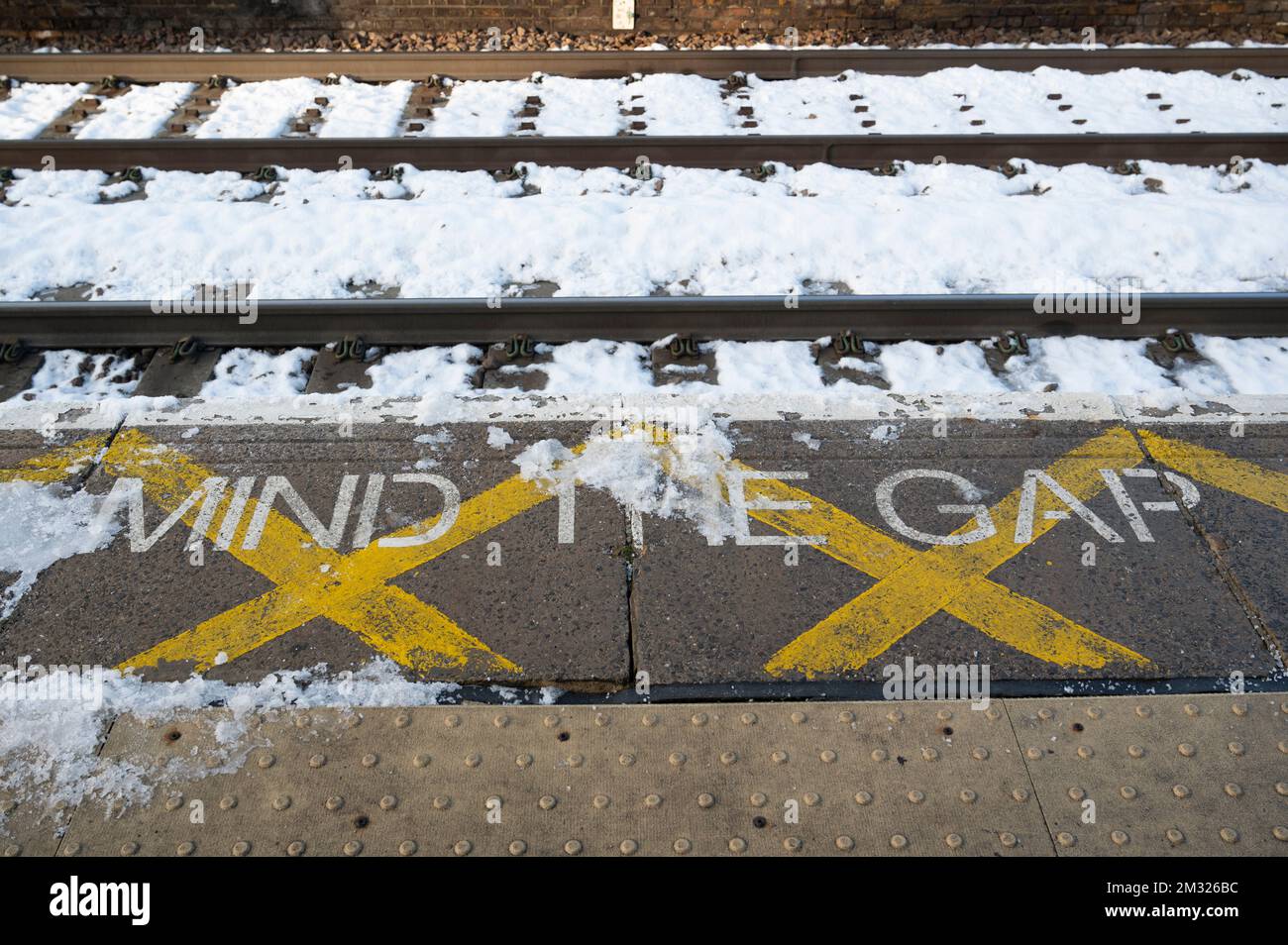 London Fields station, Hackney, London. England; UK. Train tracks and platform saying 'Mind the Gap' in the snow on a train strike day. Stock Photo