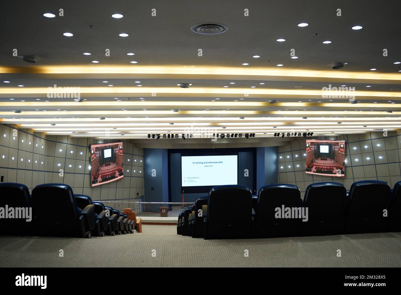 Huge and luxurious University auditorium chairs with presentation big screen. Blue theatre chairs. Stock Photo