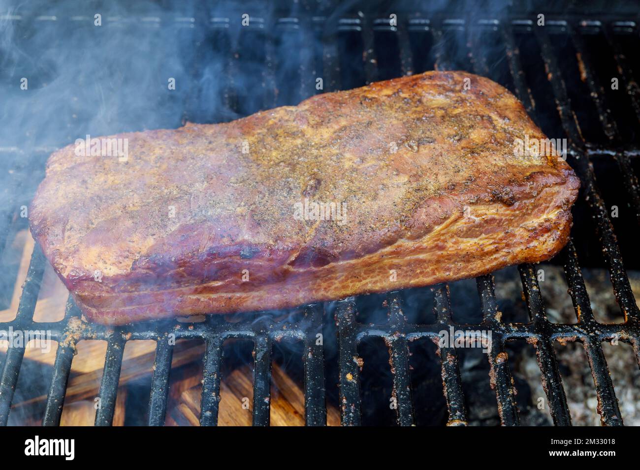 Traditional method of roasting smoked whole bacon on BBQ grill using homemade ingredients Stock Photo