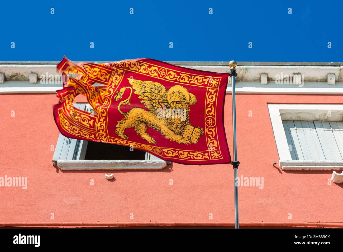 Venice lion flag, view of a flag of the Lion of Saint Mark - emblem of the city and Comune of Venice - in a street on the Venetian island of Chioggia. Stock Photo