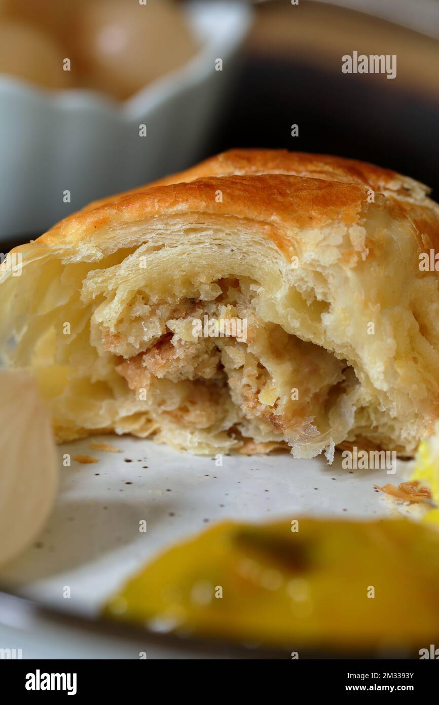 Close up shot of a freshly baked homemade meat free vegetarian sausage roll made with cheese leeks and breadcrumbs served with a variety of pickles Stock Photo