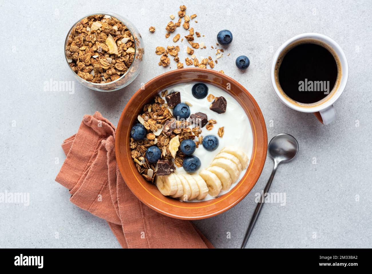 Yogurt with granola, banana, blueberries and dark chocolate chunks in a