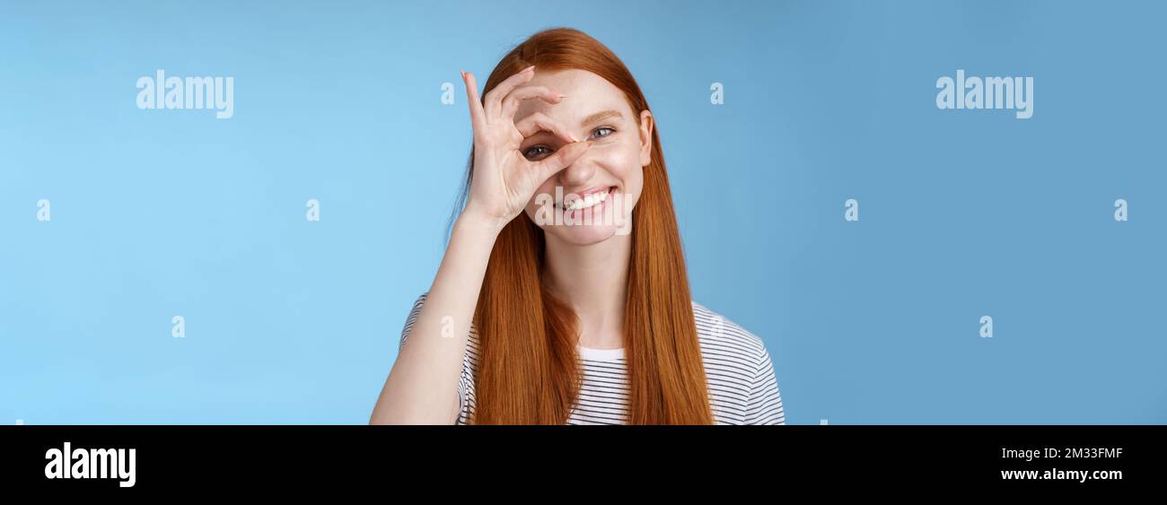 Charismatic happy adorable redhead teenage girl sincere eyes making circle eye show okay ok sign delighted like approve cool idea smiling satisfied Stock Photo