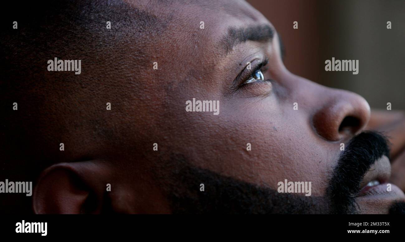 Pensive worried black African man closeup eyes looking up to sky