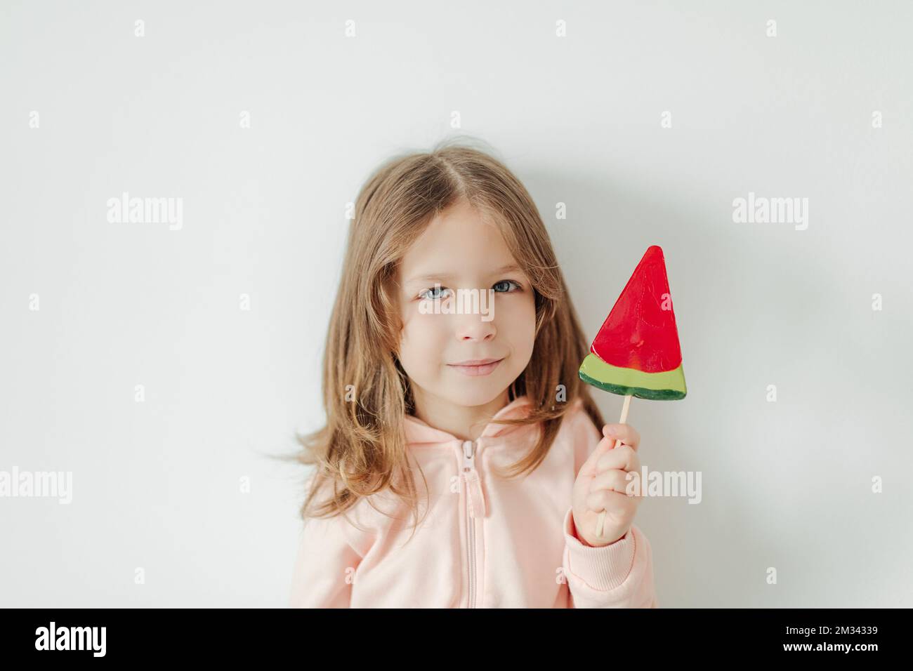 Cute little girl with watermelon lollipop. White background. Vacation and summer mood concept Stock Photo
