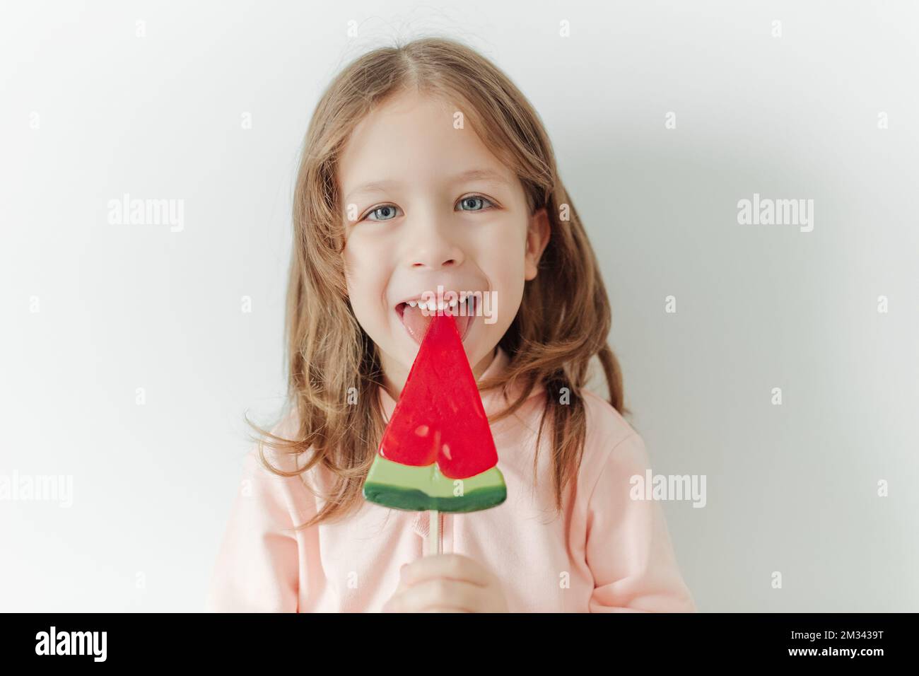 Cute happy and positive little girl with watermelon lollipop. White background. Vacation and summer mood concept Stock Photo