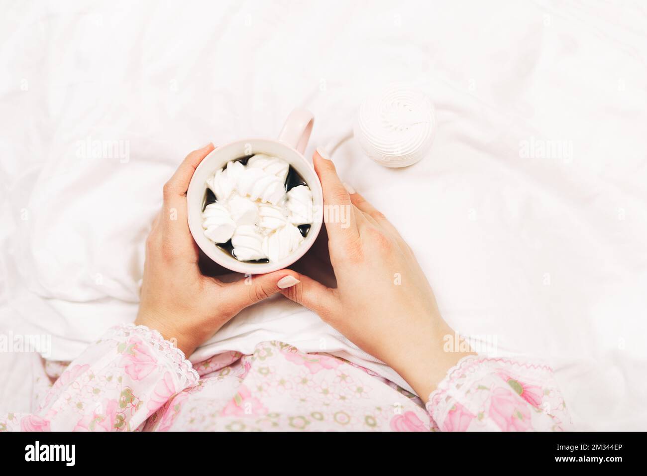 Female hands holding cup wih coffee and marshmallow.Provance romantic style.Women in bed.Top view Stock Photo