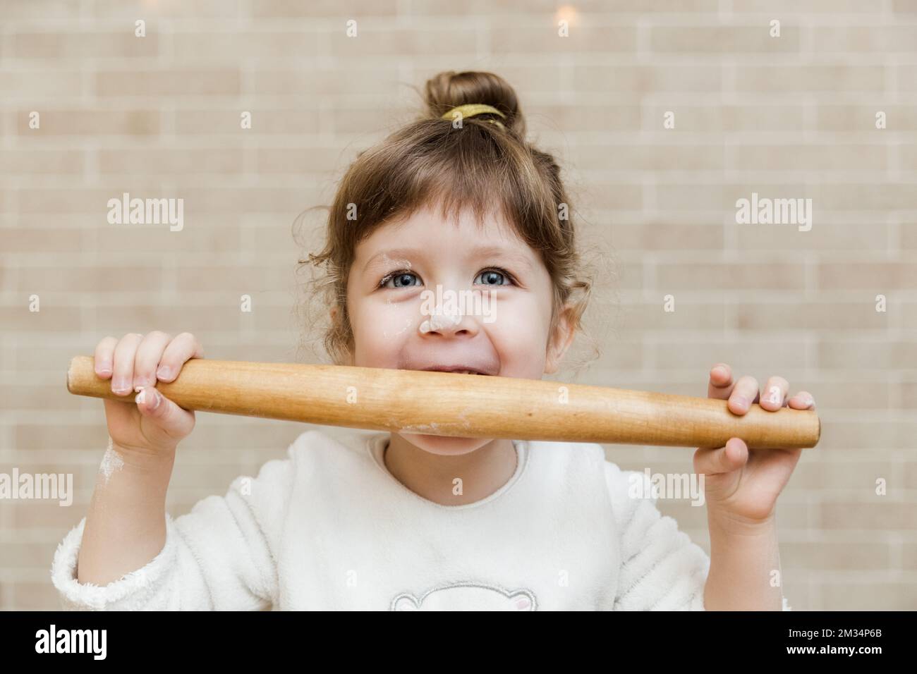 Cute baby girl is preparing in kitchen. Funny little girl is having fun