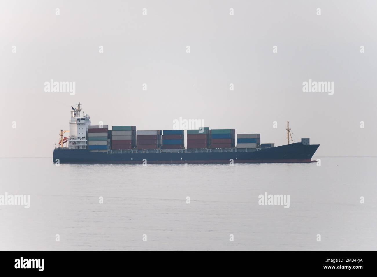 Cargo freight ship with containers and trucks sailing to industrial logistic port. Stock Photo