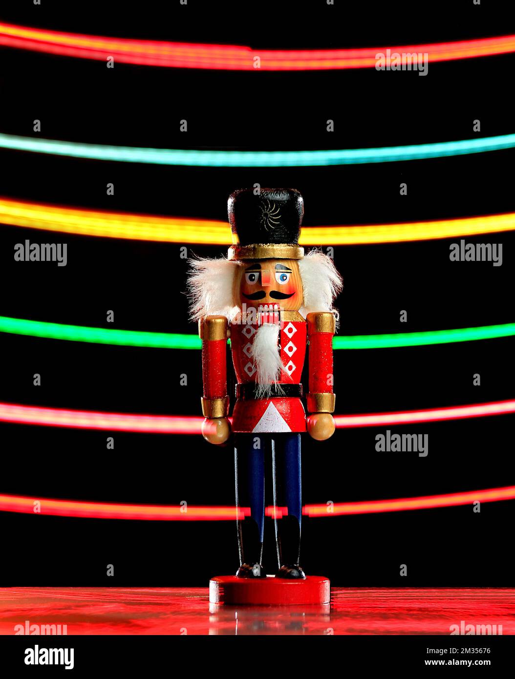 A vertical shot of a nutcracker figure with colored light streaks background Stock Photo