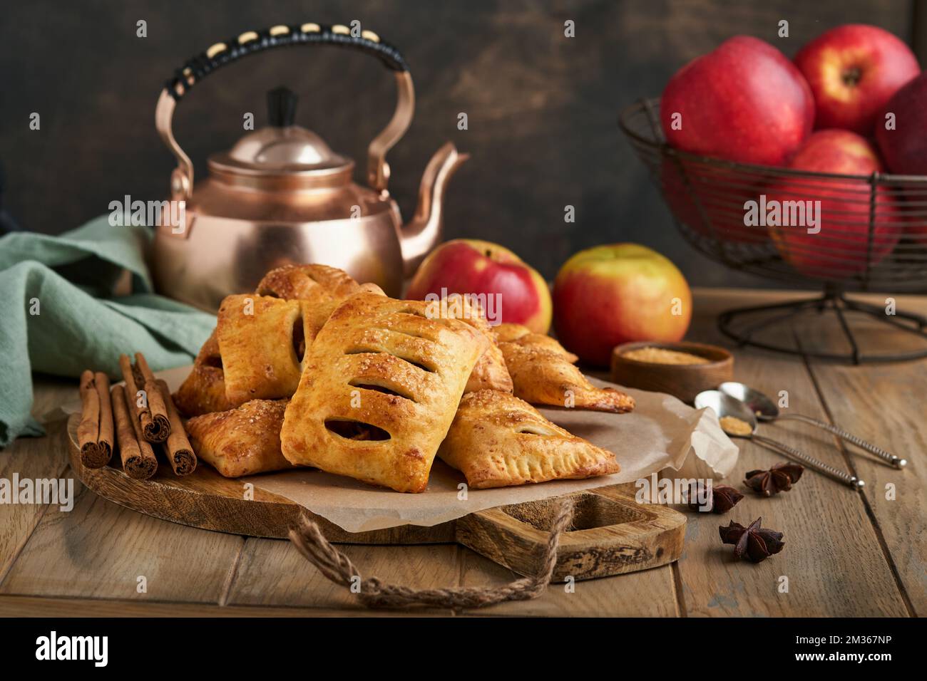 Hand pies. Mini puff pastry or hand pies stuffed with apple and sprinkle sugar powder in wooden plate. Homemade pie snack with crust for breakfast rus Stock Photo