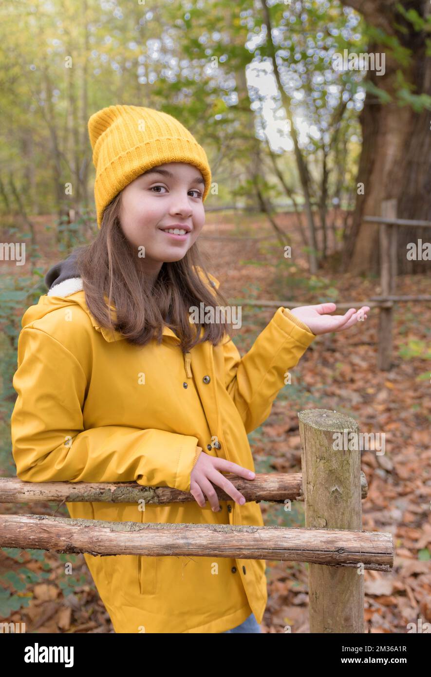 Enjoying autumn. Teenage girl on a walk in the autumn park. Frontal portrait. The model looks into the camera. bright yellow clothes Stock Photo