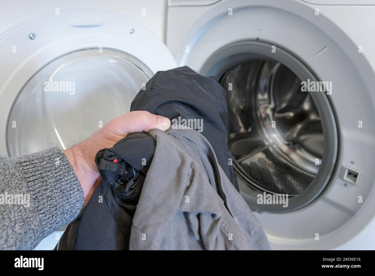 washing dark clothes. man's hand folds clothes into an open washing