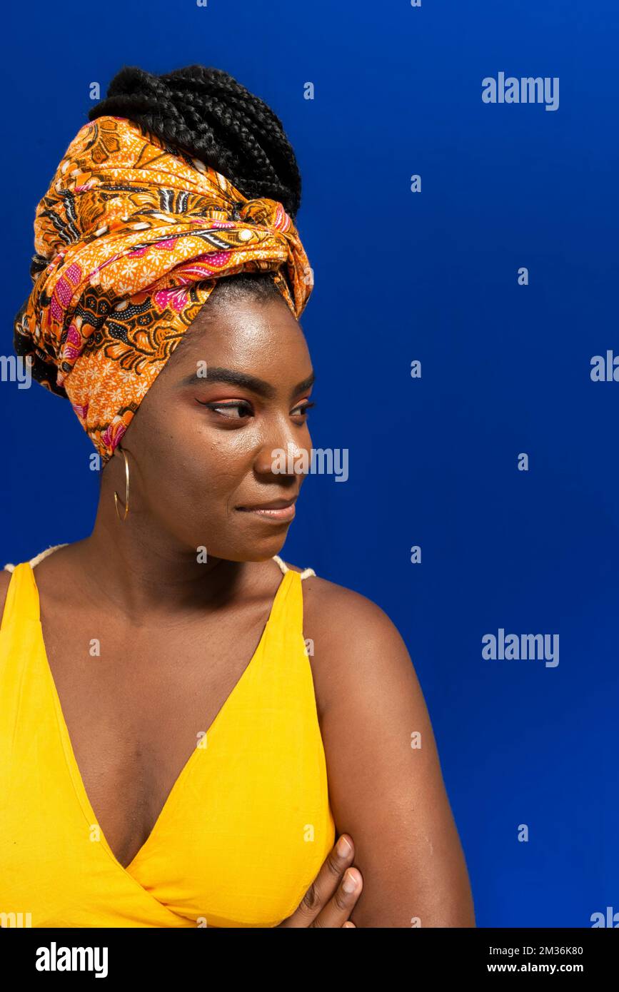 Close-up portrait of young woman, with turban on her head, against blue background. Stock Photo