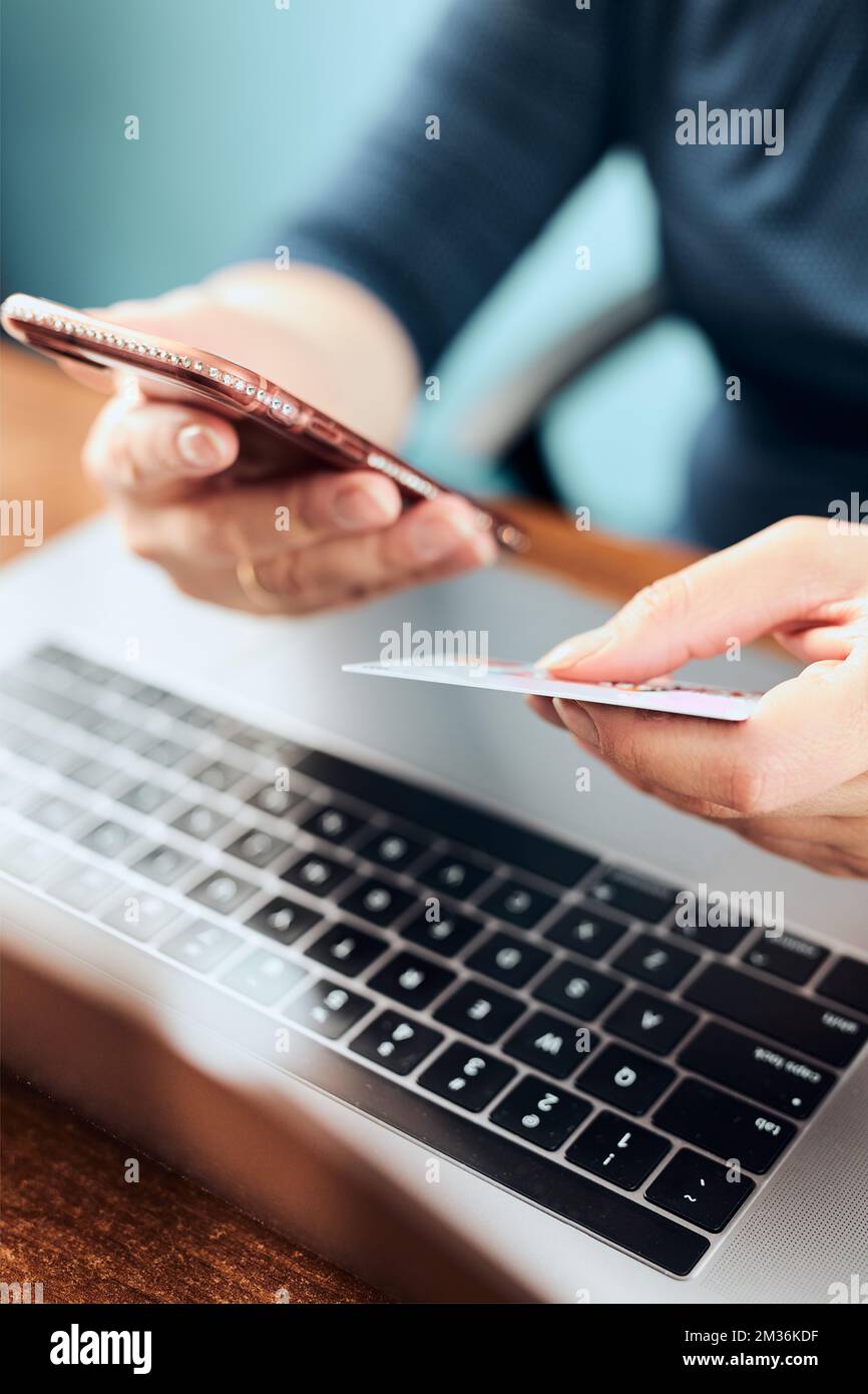 Woman doing online shopping using debit card and laptop. Female hands holding credit card over a keyboard of laptop sitting at a desk buying goods onl Stock Photo