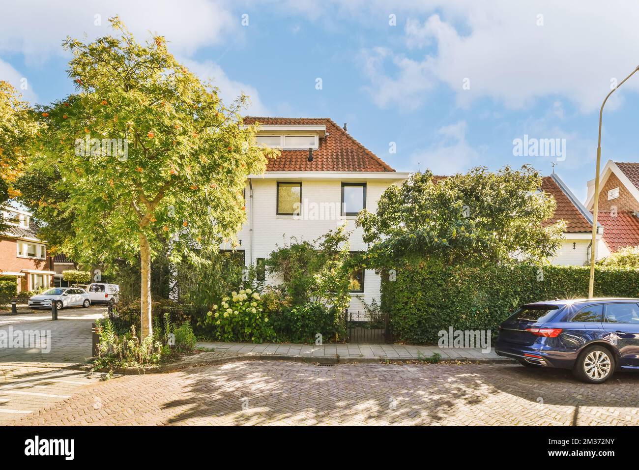 a car parked in front of a white house with red tiled roof and green ...