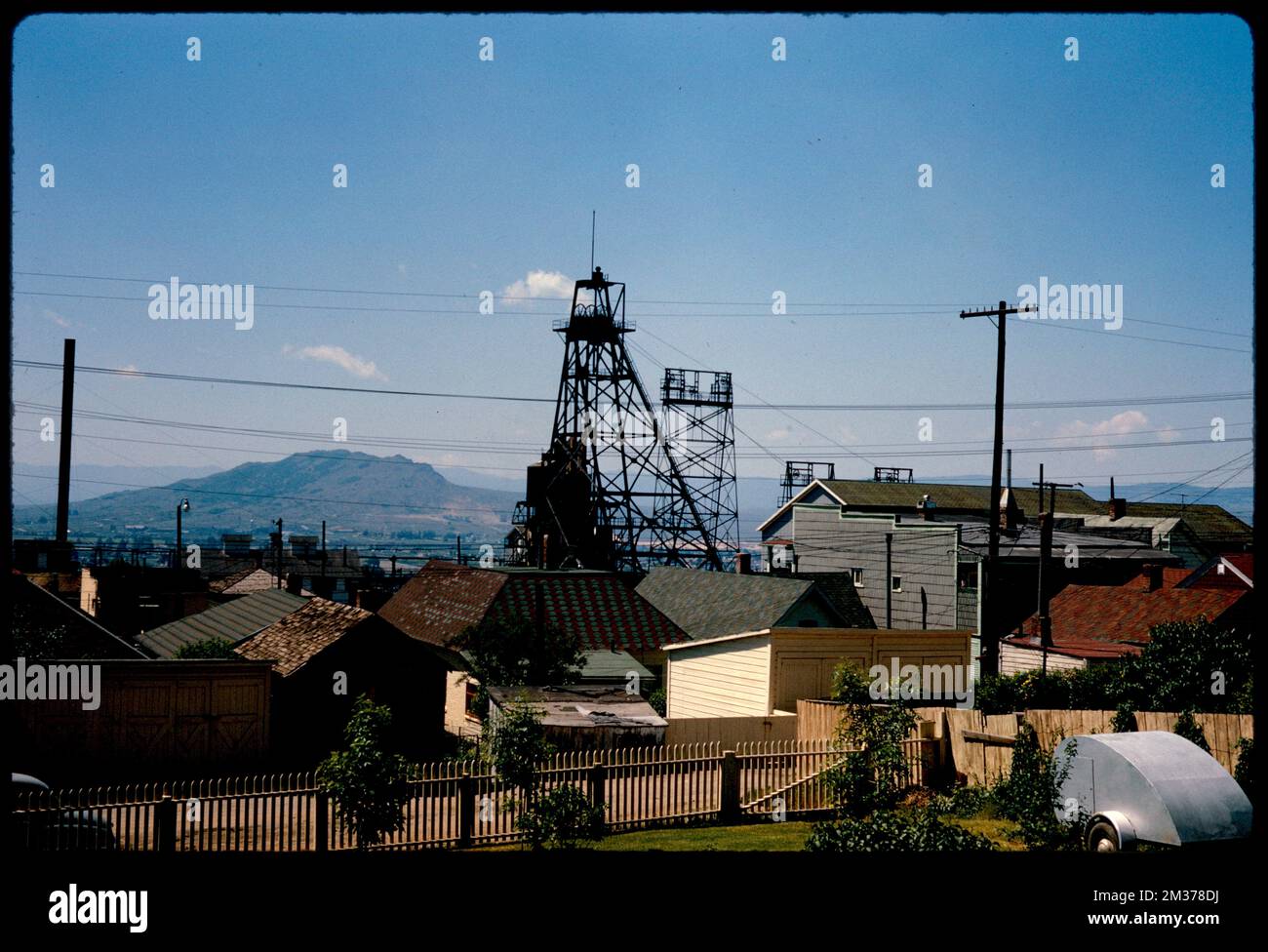 Group of buildings and mine head frames with mountains in background ...