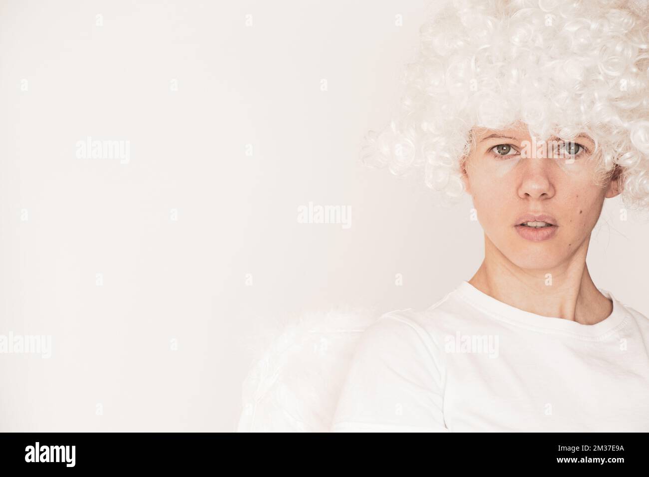 Girl dressed as an angel with wings and curly hair on an isolated ...