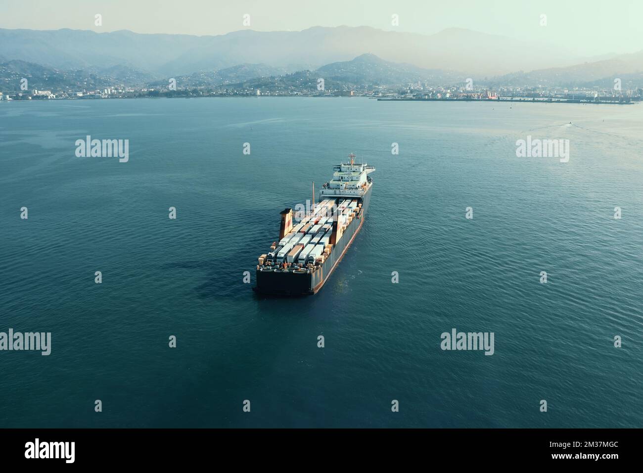 Cargo freight ship with containers and trucks, aerial view from drone. International global delivery and logistic business concept. Stock Photo