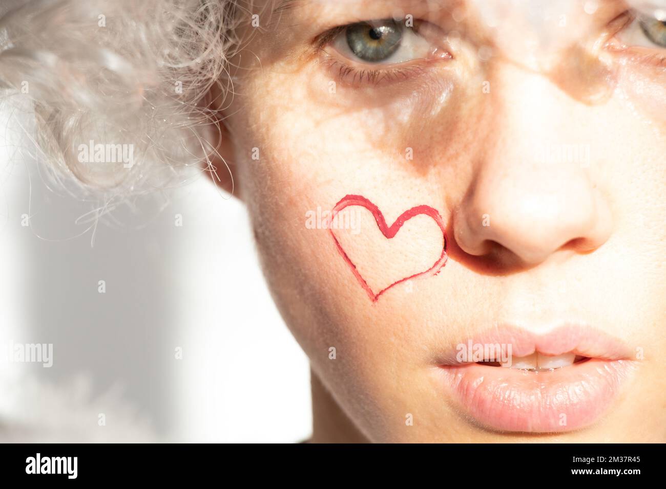 Girl dressed as an angel with wings and curly hair with a painted heart ...