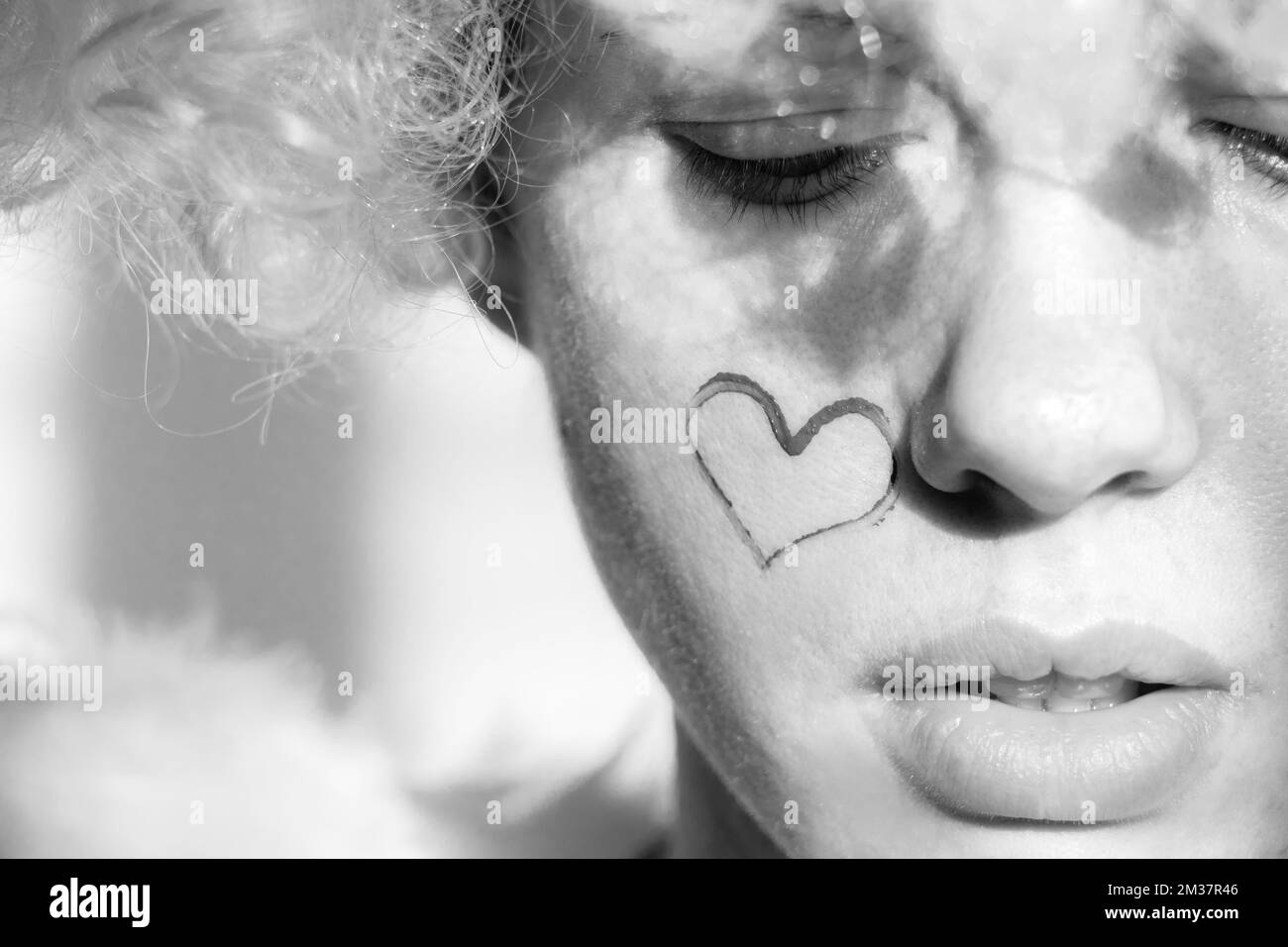Girl dressed as an angel with wings and curly hair with a painted heart ...