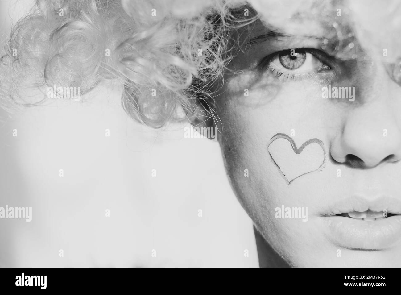 Girl dressed as an angel with wings and curly hair with a painted heart ...
