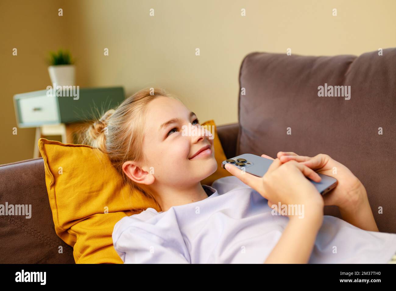 cute little girl useing smartphone and lying down on sofa in viving room at  her home Stock Photo - Alamy