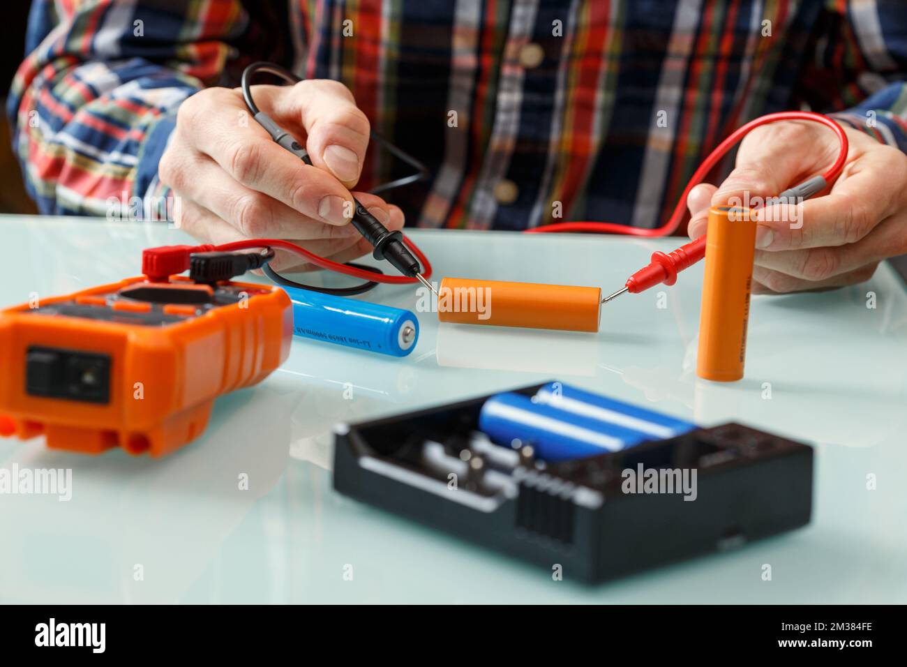 Electrician measuring battery voltage with a multimeter. Home master and portable power efficiency coincept Stock Photo