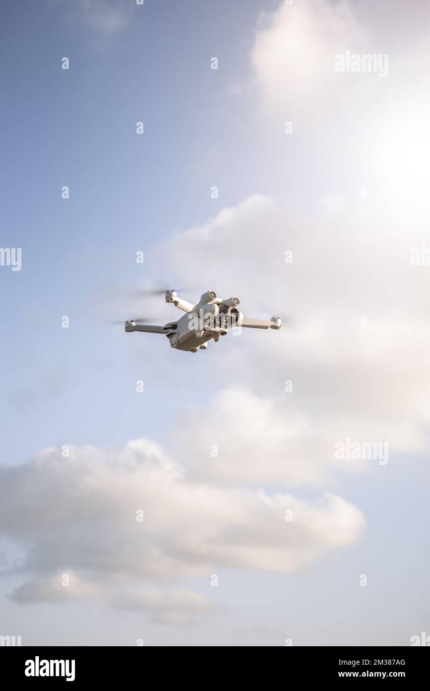 A vertical shot of a quadcopter flying in the sky in a sunny day Stock Photo