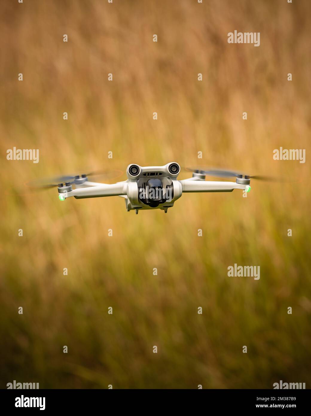 A selective vertical shot of a quadcopter flying over a blurry field Stock Photo