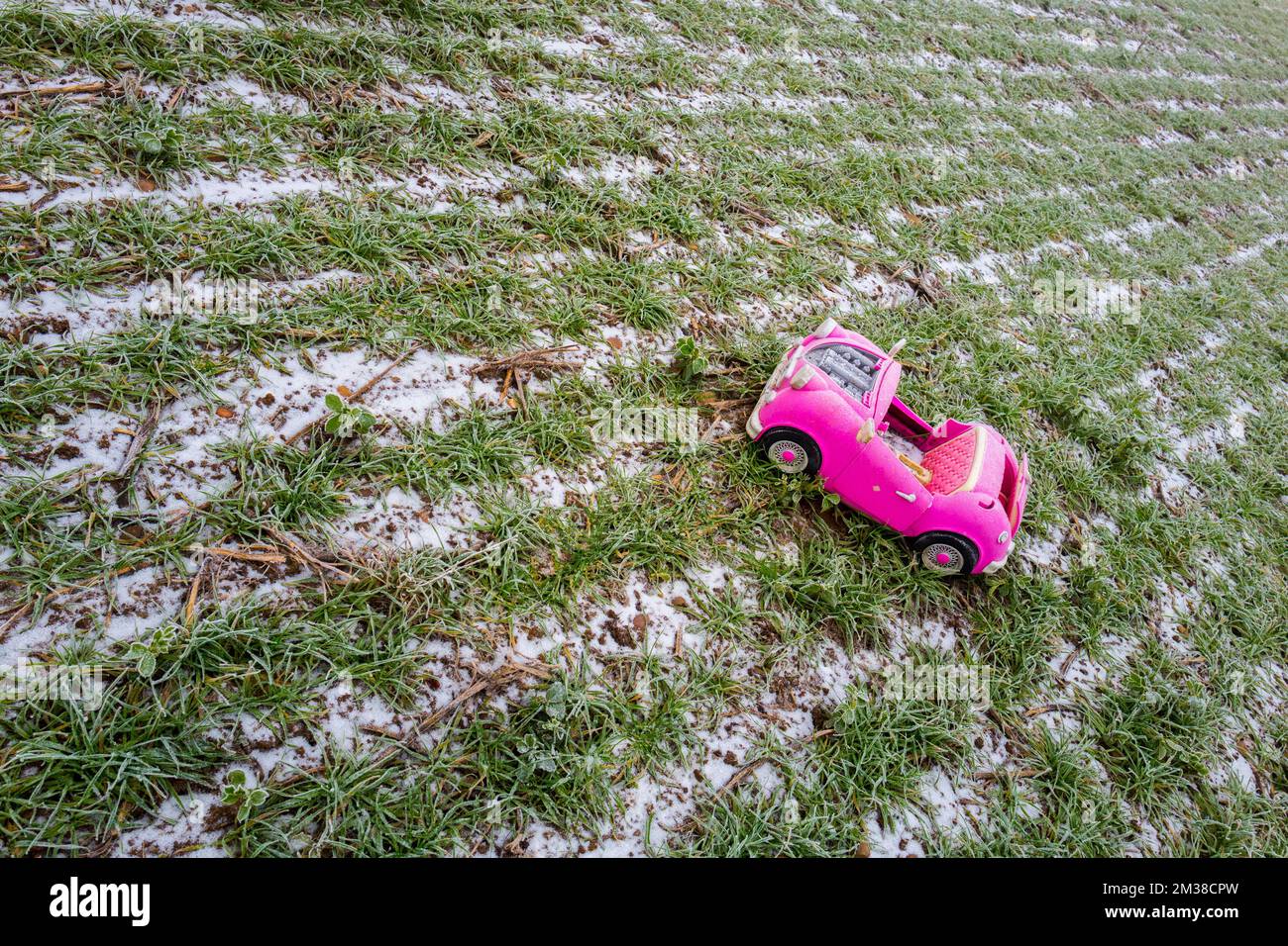 Pink retro convertible plastic toy car for 18-inch dolls by Og Girl dumped in a field on a cold, frosty day. Stock Photo