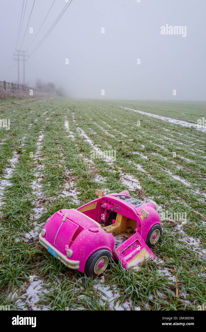 Pink retro convertible plastic toy car for 18-inch dolls by Og Girl dumped in a field on a cold, frosty day. Stock Photo