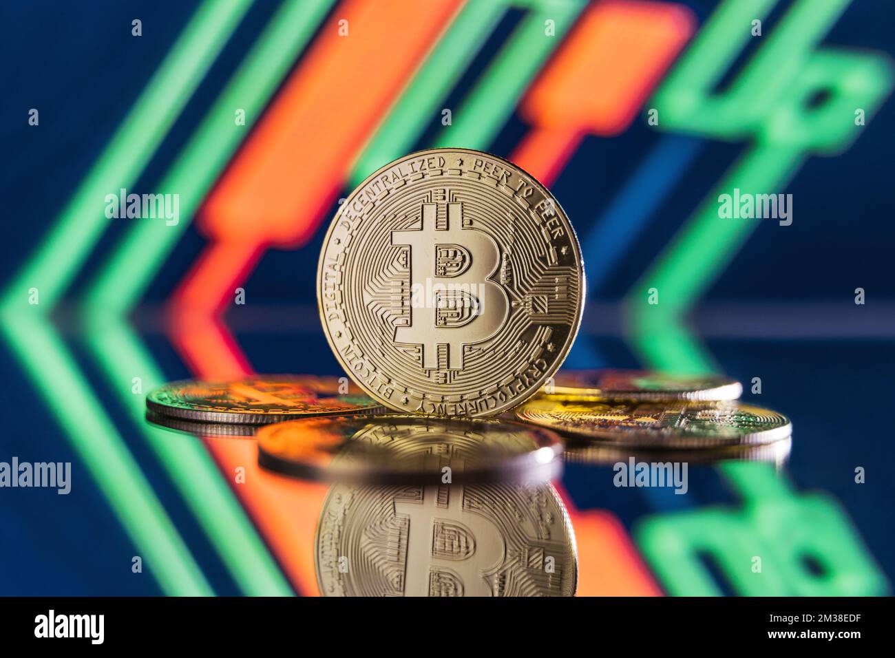 Image of bitcoins lying on mirror surface with one one standing isolated on blurred background with red and green candlesticks on digital crypto chart Stock Photo