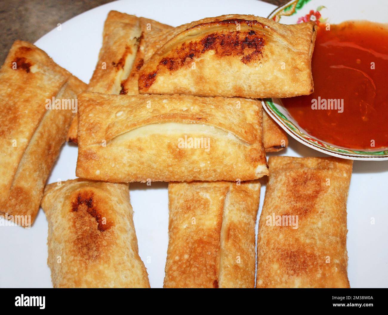 Crispy baked egg rolls with a side dish of plum sauce Stock Photo