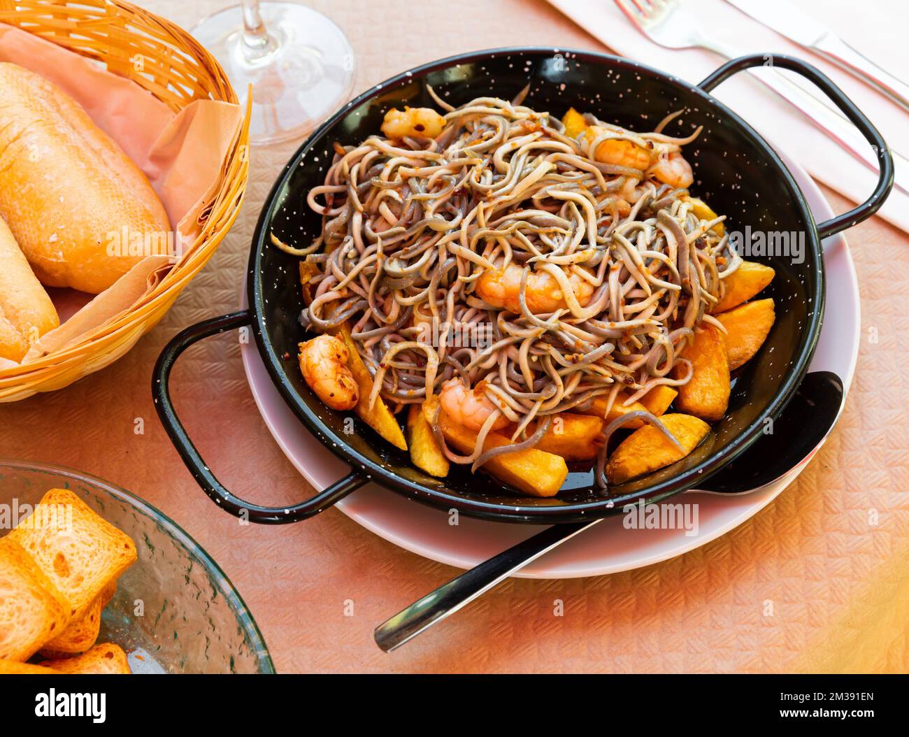 Plate of tasty fried baby eels and prawns with potatoes Stock Photo