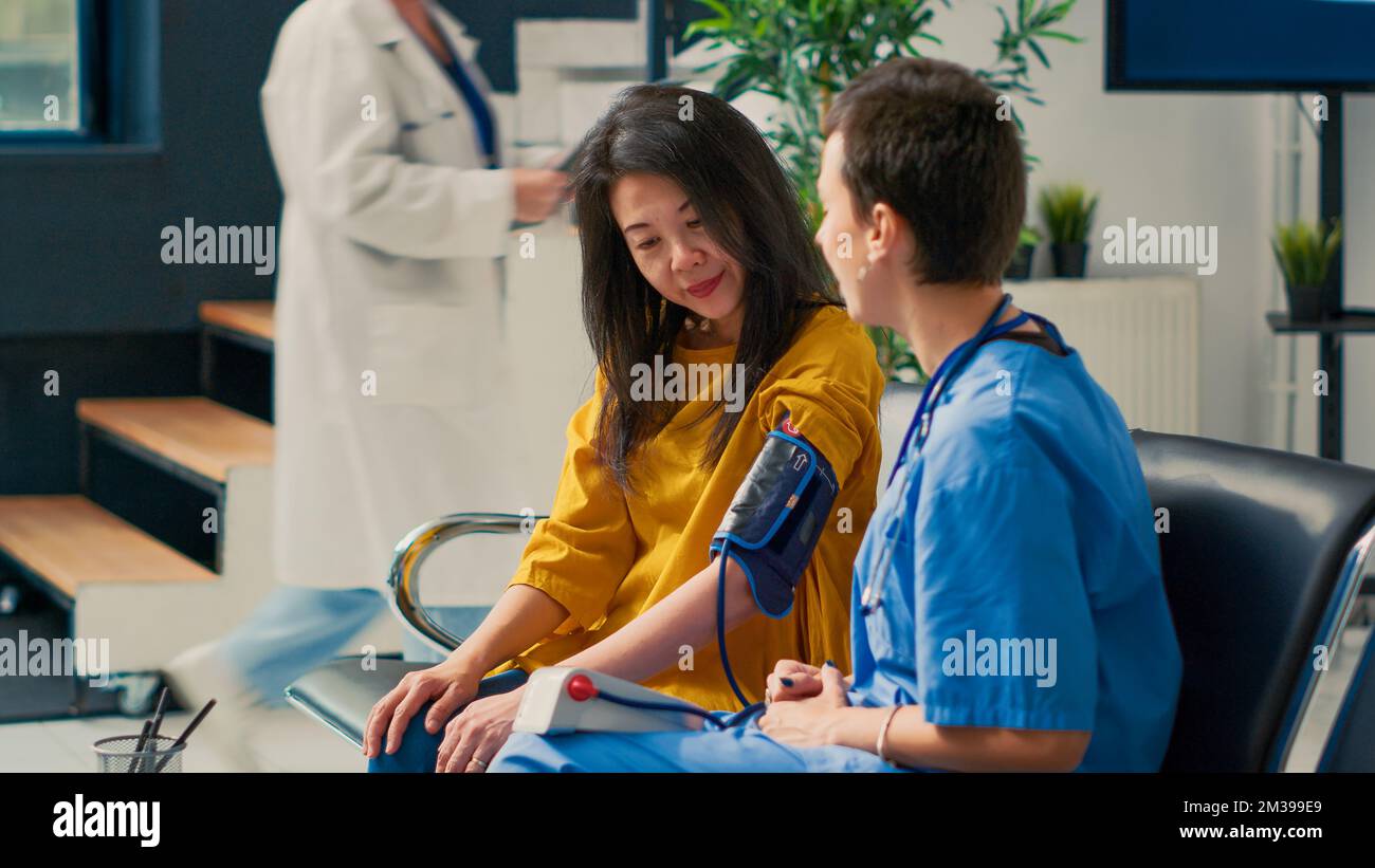 Female nurse doing cardiology consultation with asian patient in ...