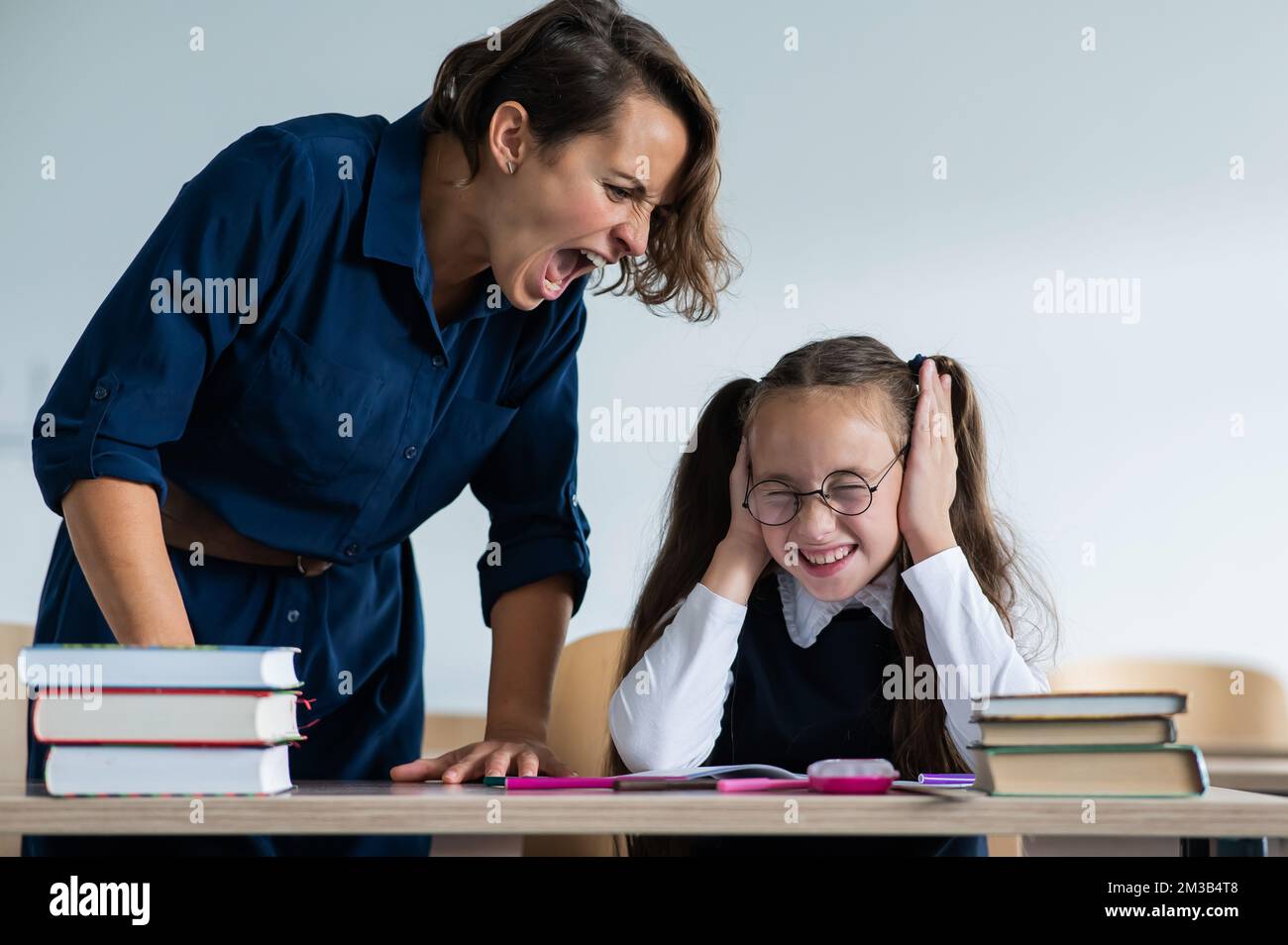 A female teacher yells at a student. Little girl covers her ears with