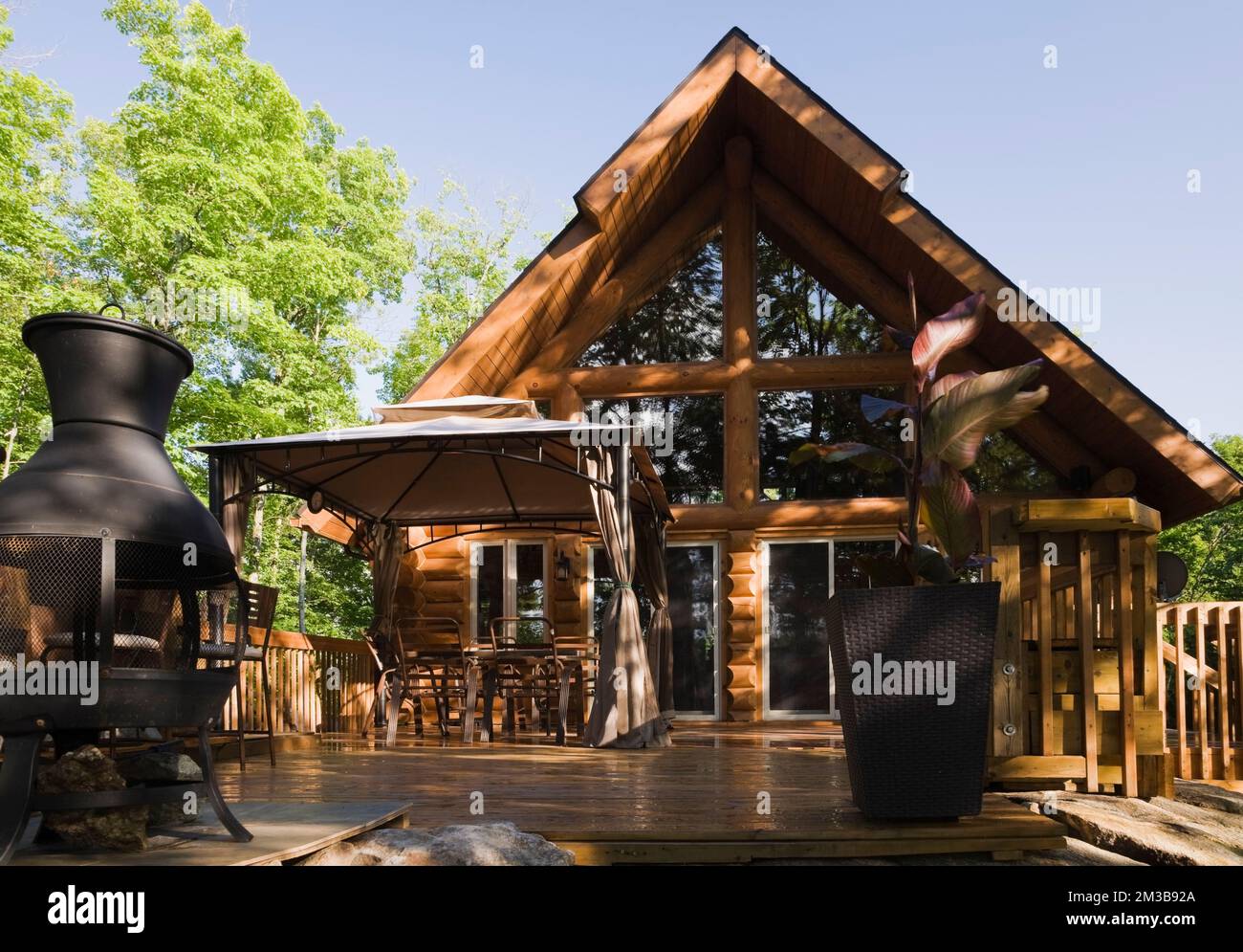 Aframe style log cabin with watered down wooden deck in summer Stock