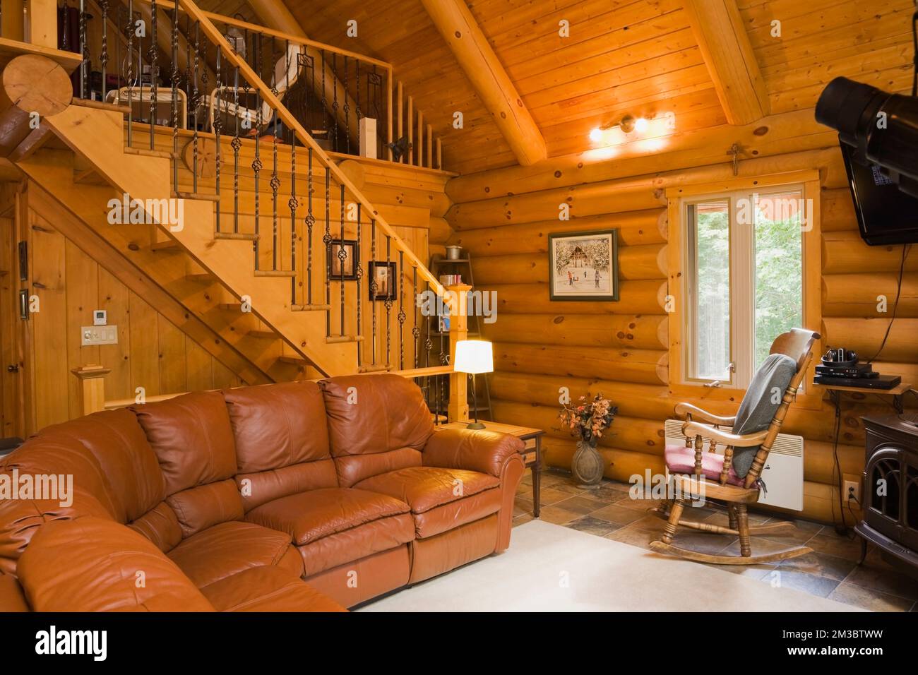 Dark tan leather sofa in living room and staircase leading to upstairs