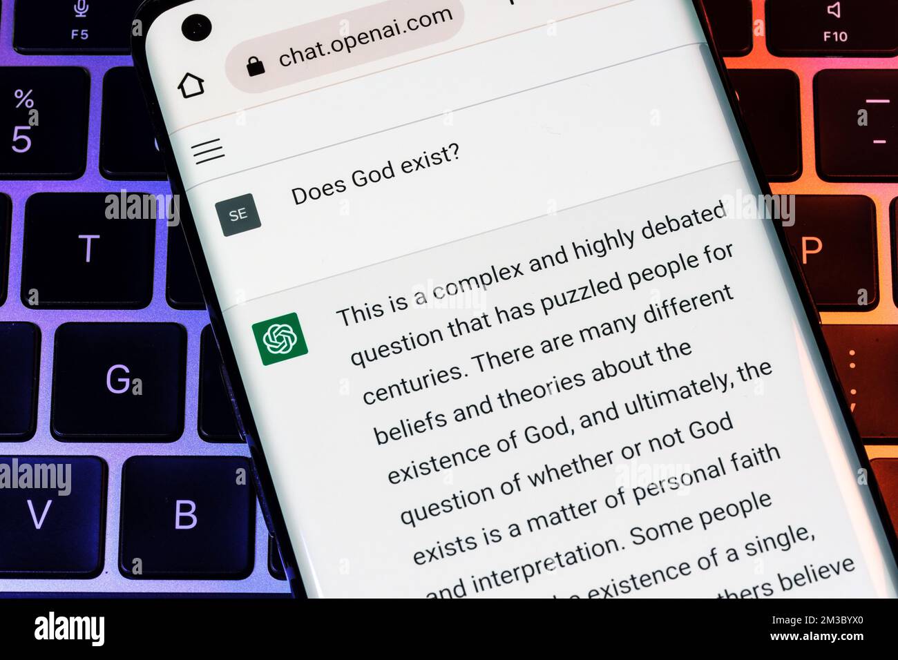 OPEN AI ChatGPT chat bot seen on smartphone placed on laptop. AI chatbot responded to the question about God's existence. Stafford, United Kingdom, De Stock Photo