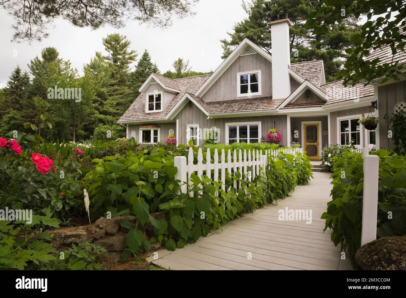 New Hampton cottage style home with landscaped front yard and wooden