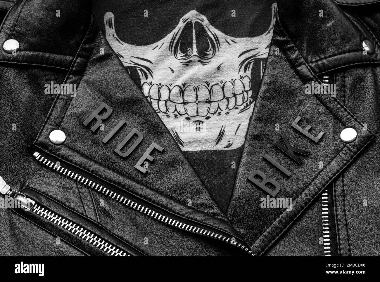 closeup to ride bike lettering over biker leather jacket and skull kerchief. motorcycle style, black and white photography Stock Photo