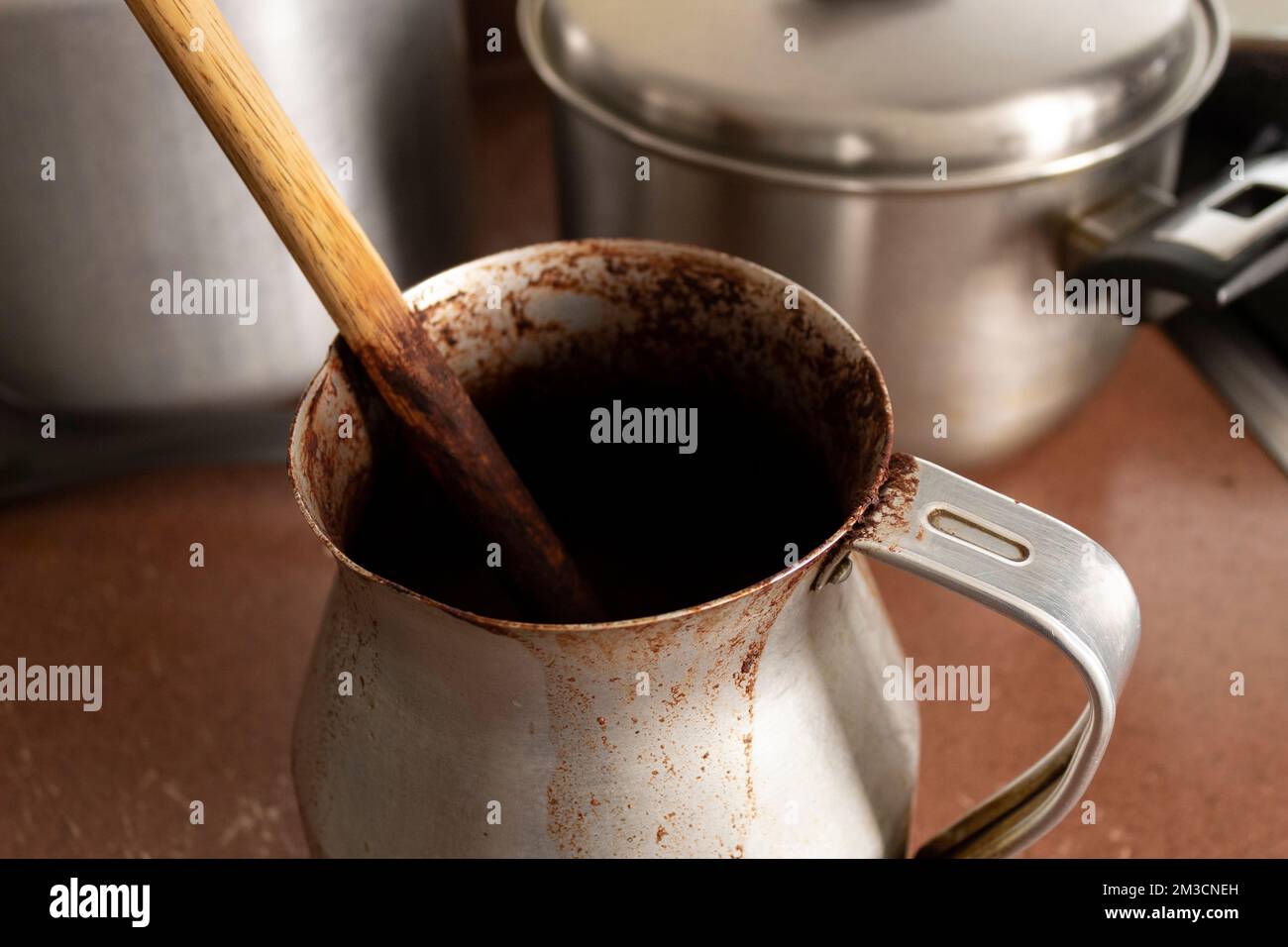 https://c8.alamy.com/comp/2M3CNEH/close-up-to-an-old-dirty-cocoa-cooking-pot-over-kitchen-furniture-with-others-cooking-pots-at-background-traditional-kitchen-concept-2M3CNEH.jpg
