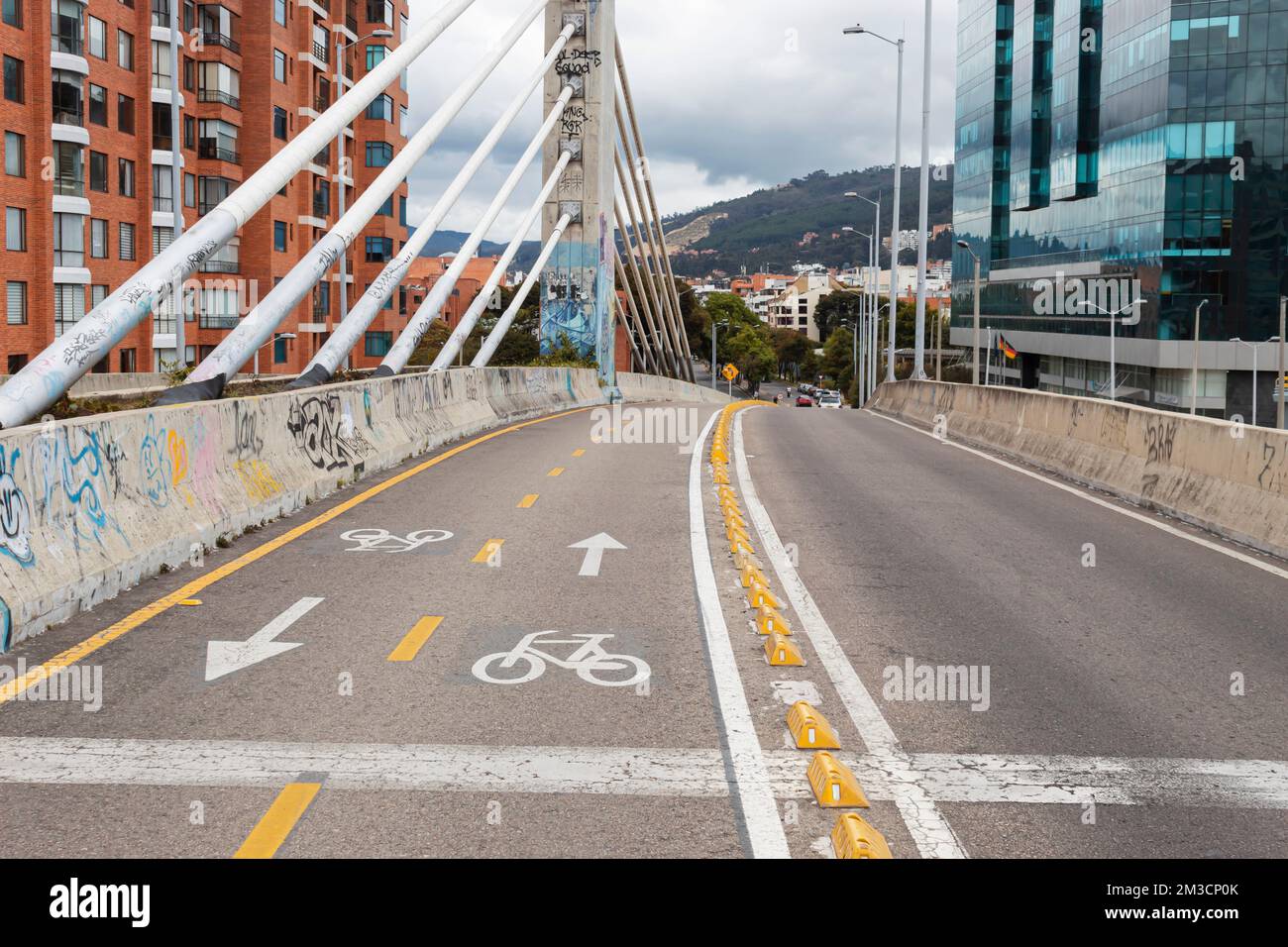 BOGOTA, COLOMBIA - A bike way over a vehicular bridge near to a moder building and residential brick buildings Stock Photo