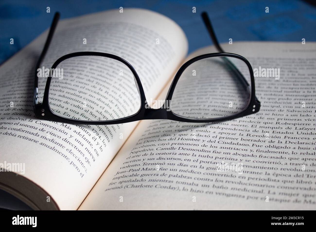 Closeup to a black reading glasses over a spanish text open book with